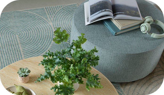 duck egg blue round footstool with a book on top and a stone effect round coffee table with plant on top