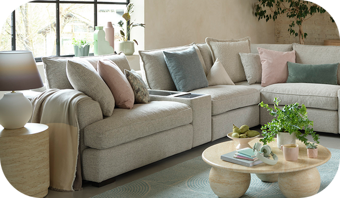 light grey corner sofa next to a light blue rug and different colour pastel scatter cushions