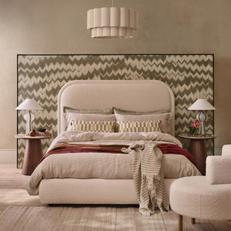 boucle bed against a patterned green mural with dark wood bedside tables
