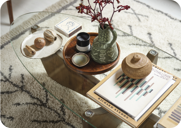 Glass coffee table with dark wood legs finished with a variety of accessories and ornaments