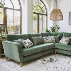 green corner sofa with wooden legs and monochrome pattern scatter cuhshions