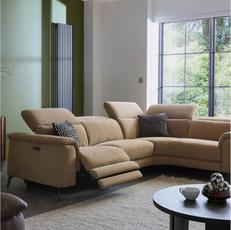 brown corner power recliner sofa next to a large window and on a fluffy rug
