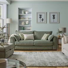 sage green fabric sofa next to a pale green wall with built in shelves next to a fluffy white rug