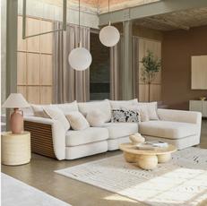 white corner sofa with built in wooden panelling on the arm next to a cream marble side and coffee table