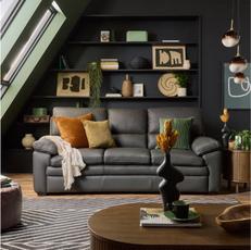 black leather sofa against a black wall with built in shelves next to patterned monochrome rug