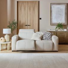 white leather recliner sofa next to a white fluffy rug against a light oak door