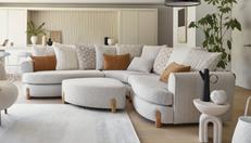 Light grey boucle curved corner sofa with wooden feet in a modern neutral living room