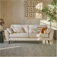 Cream boucle sofa in a modern neutral living room with orange scatter cushions