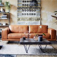 Brown leather sofa with square block arms in a modern neutral living room with black coffee table