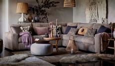 Soft faux fur corner sofa in a cosy living room with fur rug and rattan lighting