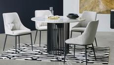 Black and white round dining table with 4 fabric dining chairs sat above a monochrome rug