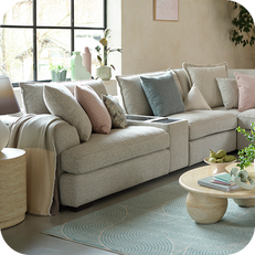 grey corner sofa with pink and green pastel coloured cushions