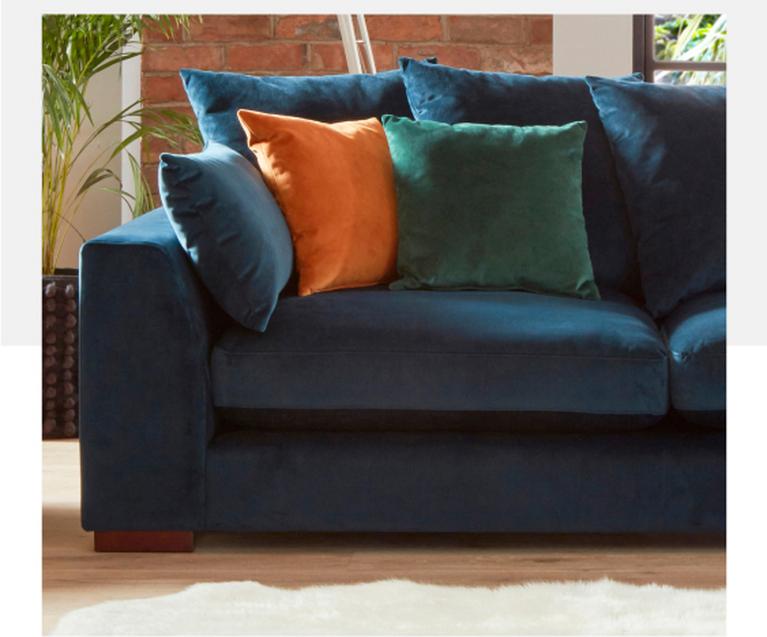 Dark blue velvet chaise sofa with green, orange and blue scatter cushions