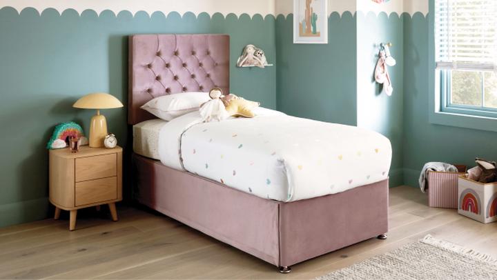 Pink velvet single bed in a childs bedroom with turquoise walls and white duvet with coloured hearts