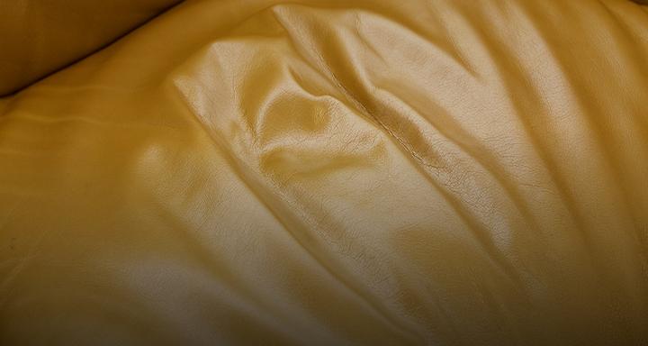 close up of a worn yellow leather sofa