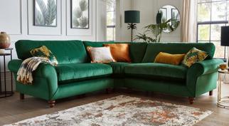 dark green velvet corner sofa with orange scatter cushions