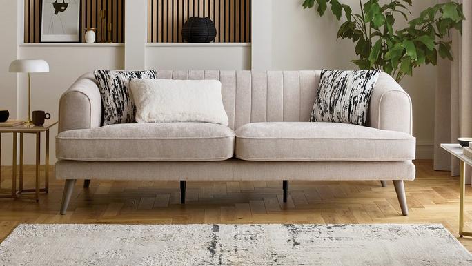 Cream chenille sofa with black and white cushions, sat on a wooden floor and fluffy rug