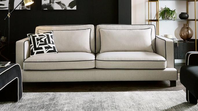 white fabric sofa with black piping situated in a monochrome space
