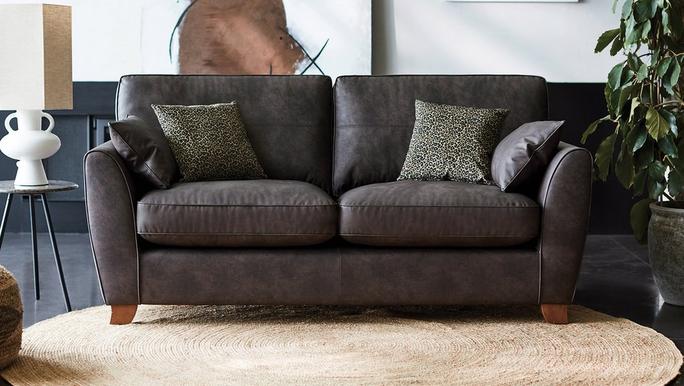 Dark brown faux leather sofa on a yellow fluffy rug with green pattern scatter cushions