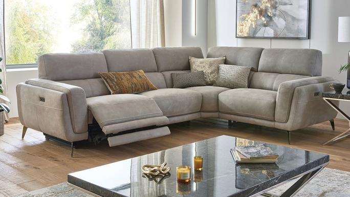 Light grey power recliner corner sofa on a wooden floor next to a glass coffee table