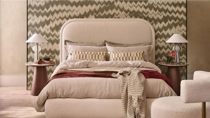 boucle divan bed against a green pattern wall mural with dark wood bedside tables