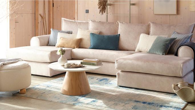 beige u shaped sofa with blue and beige scatter cushions on a blue patterned rug