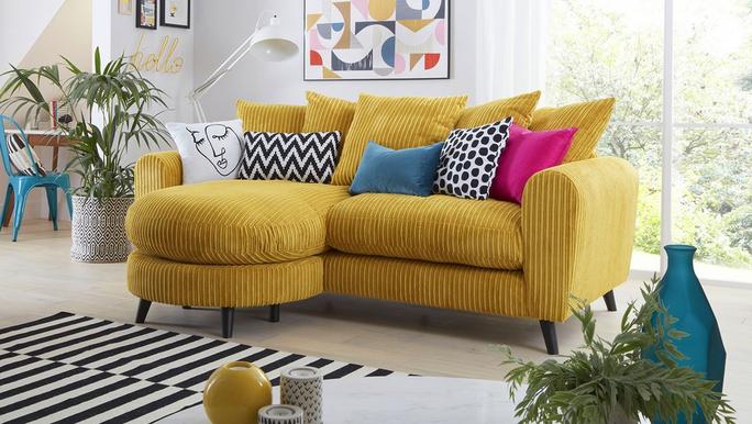 Yellow jumbo cord sofa with a variety of multi coloured scatter cushions