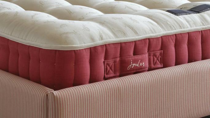 Close-up of a plush mattress with a cream-colored top and a deep pink side