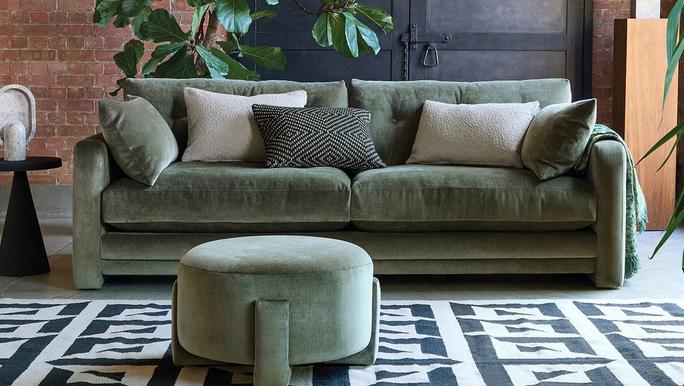 green sofa with matching round football next to a patterned rug and multi green scatters