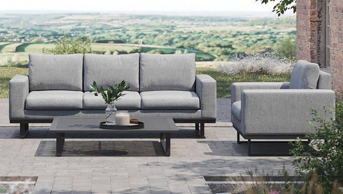 Light grey garden sofa with black legs and coffee table with a scenic field in the background