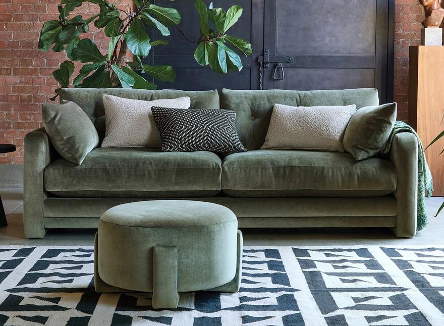 green sofa with matching round footstool on a patterned monochrome rug