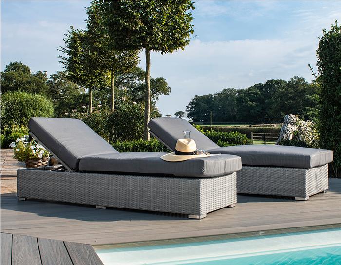 Dark grey rattan sunlounger next to a pool