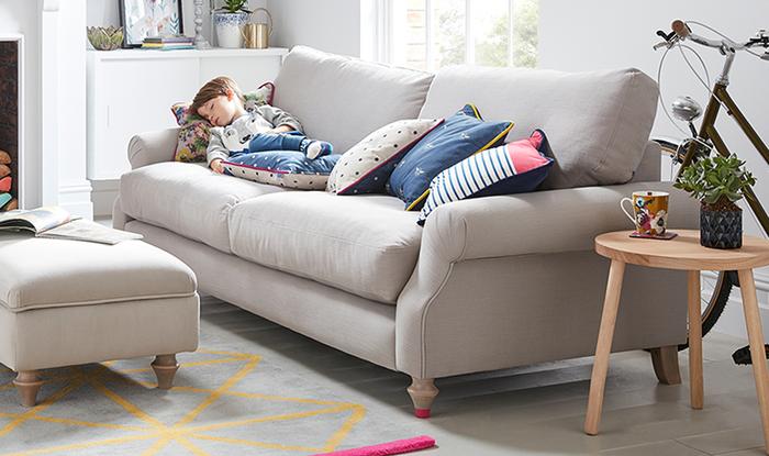 Young boy fast asleep whilst laid on a beige fabric sofa
