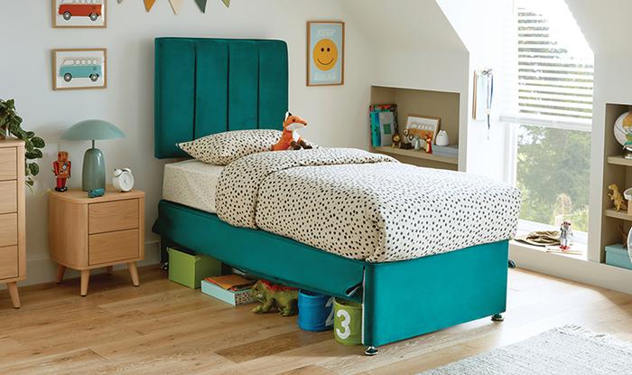 Teal childrens kid with black polka dot bedding and a wooden bedside table with toys underneath the bed