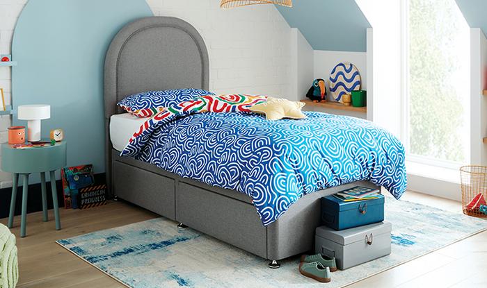 Grey childrens with circular headboard with blue patterned bedding and blue patterned rug