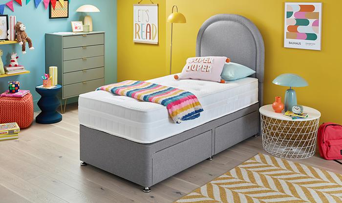 Single mattress on a grey single bed with multicoloured throw in a colourful childrens bedroom