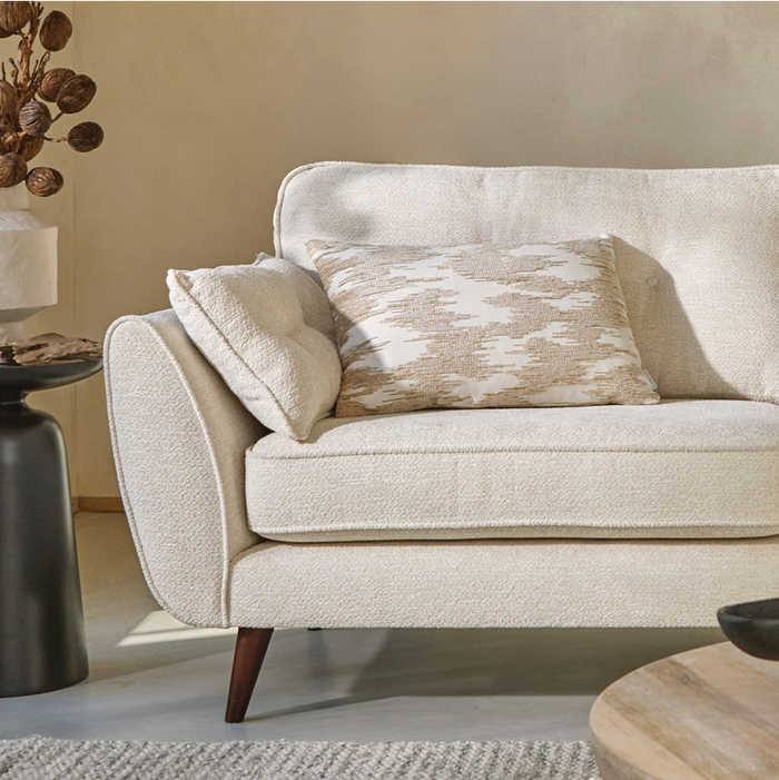 close up shot of a cream boucle sofa with dark wood angled feet