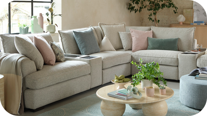light grey corner sofa next to a pale blue rug and finished with pastel scatter cushions