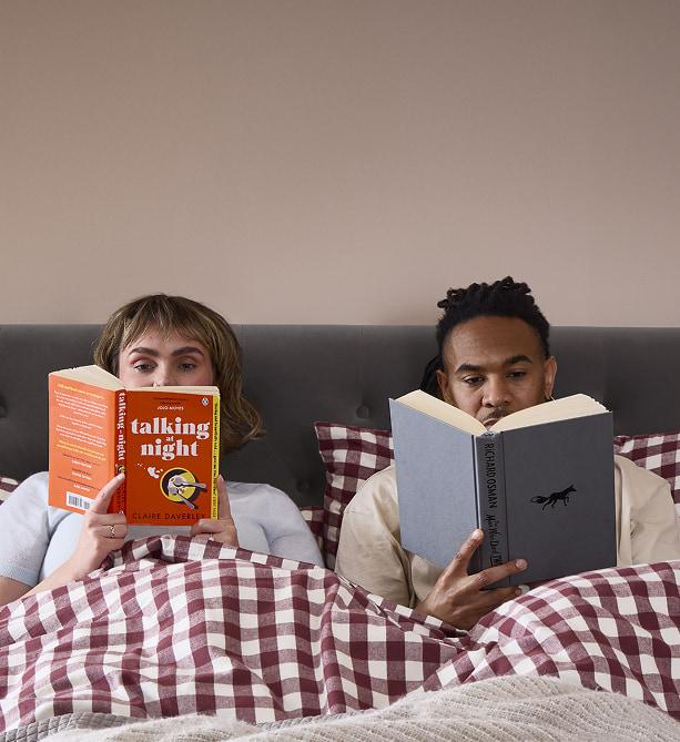 Couple sitting up in bed reading books
