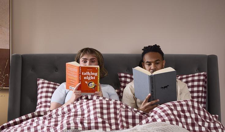 Couple sitting up in bed reading books