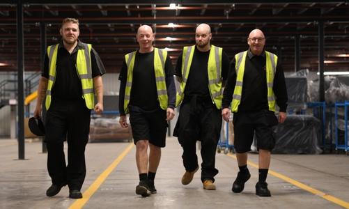 Four workers walking through warehouse